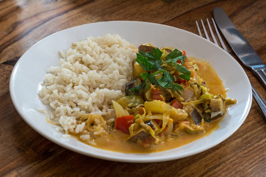 dish with vegetable curry and rice on a wooden table