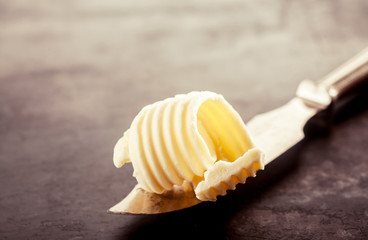 Butter on a Knife on Top of a Wooden Table - obrazy, fototapety, plakaty