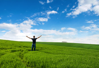 Man stands in the middle of a green meadow