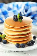 Delicious pancakes with blueberries on white wooden background