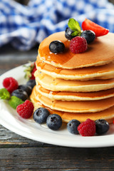 Delicious pancakes with berries on blue wooden background
