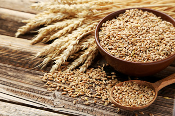 Wheat in bowl on brown wooden background