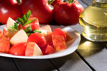 Tomato and apples in a bowl on a dark table. 