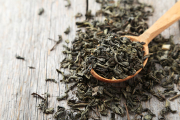 Dry tea in spoon on grey wooden background