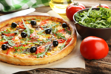 Fresh tasty pizza on brown wooden background