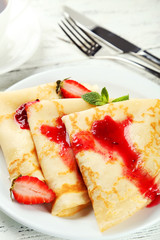 Pancakes with strawberry on plate on white wooden backgound