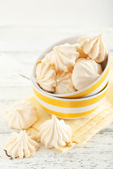 French meringue cookies in bowl on white wooden background