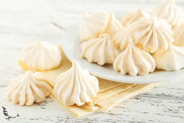 French meringue cookies on plate on white wooden background
