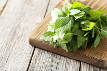 Basil leaves on cutting board grey wooden background