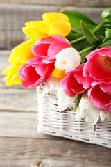 Fototapeta na wymiar Beautiful tulips in basket on grey wooden background