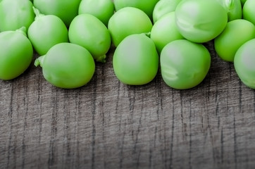 Green organic peas on wooden background, shalow focus