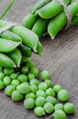 Green organic peas on wooden background, shallow focus