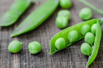 Green organic peas on wooden background, shallow focus