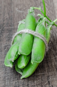 Green organic peas on wooden background, shallow focus