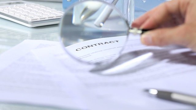 looking through a magnifying glass to contract, hand signature
