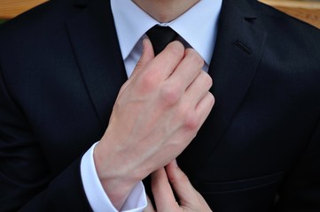 a man in a suit straightens his tie
