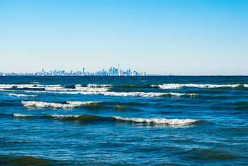 Waves breaking on lake with Toronto skyline in distance.