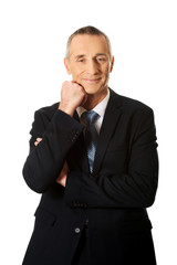 Happy mature businessman with hand under chin
