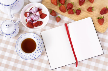 Strawberries and cream with blank recipe book or cookbook notepad or journal making preparing summer fruit dessert photo