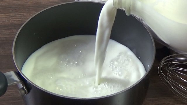 Slow motion of milk being poured into a pan
