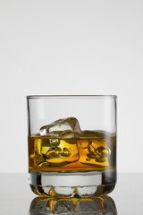 Glass of whisky with ice on white background
