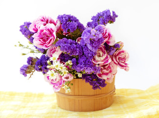 Bunch pink and blue flowers in wooden bucket. 