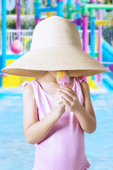 Child with hat eating ice cream at pool
