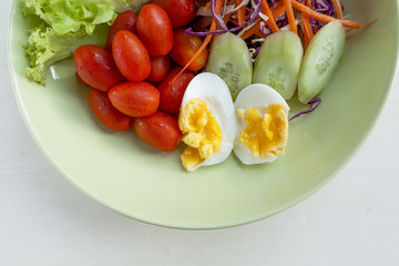 Fresh vegetable salad with egg in green plate 