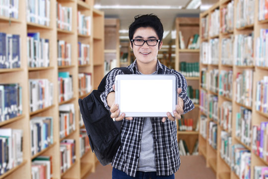Student showing tablet screen in library