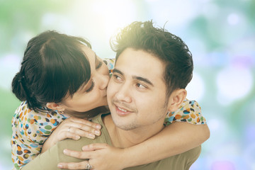 Fototapeta premium Woman kiss her boyfriend with bokeh background