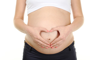 Pregnant woman showing heart by hands on belly 