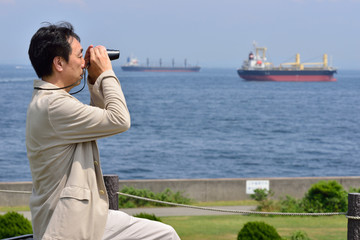 双眼鏡で海を眺める日本の男性