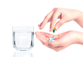 Drug capsules and pills in hand with drinking water