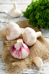 Garlic and a bunch of parsley on a white table