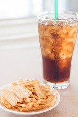 Snack on white plate with a glass of cola