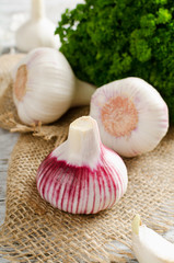 Garlic and a bunch of parsley on a white table