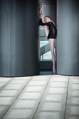 Fototapeta na wymiar Young graceful ballerina in black bathing suit on a background o