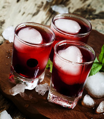Red berry juice with ice in the shape of hearts, selective focus