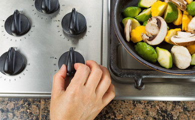 Turning on natural gas stove to cook vegetables