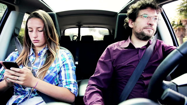Father driving car angry with daughter chatting with phone