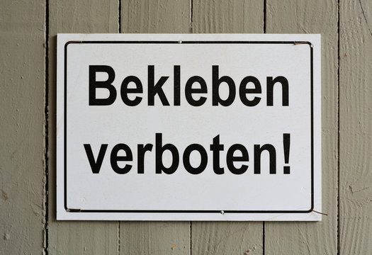 Schild mit der Aufschrift "Bekleben verboten" an einem Zaun