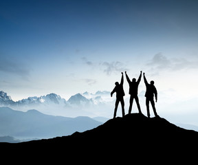 Silhouettes of team on mountain peak