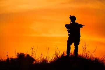 Fototapeta na wymiar Silhouette of military soldier or officer with weapons at sunset