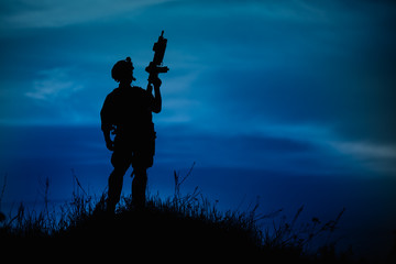 Fototapeta premium Silhouette of military soldier or officer with weapons at night.