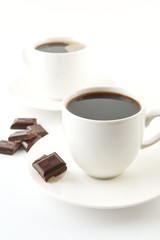 Cups of coffee with chocolate and saucers on white