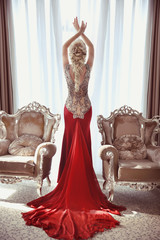 Indoor full length portrait of elegant blond woman in red gown w