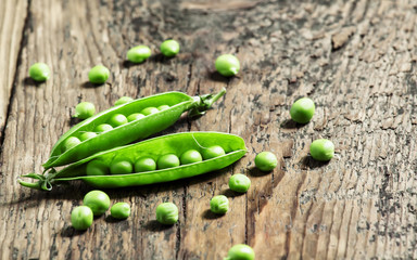 Opened green pea pods with peas in an old wooden table, selectiv