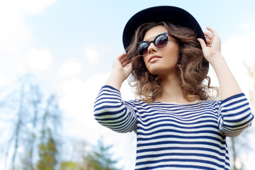 bright happy girl in hat and sunglasses walking in the park