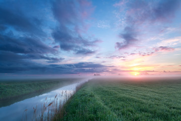 misty sunrise over meadow and river