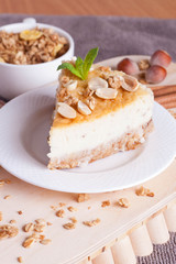 piece of cheesecake with nut on wooden board, vertical